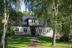 ein großes weißes Haus mit einem Baum davor in der Unterkunft Barnens Ö in Väddö