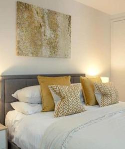 ein Bett mit Kissen und ein Gemälde an der Wand in der Unterkunft Westminster 2 bed 2 bath apartment in London