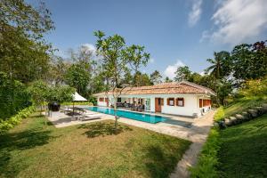 a house with a swimming pool in a yard at Nyne Hotels - Leela Walauwwa, Induruwa in Induruwa