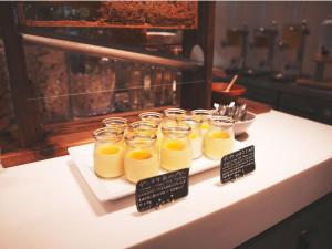 石垣岛The BREAKFAST HOTEL MARCHE Ishigaki Island的桌子上摆着一组装满橙汁的玻璃罐