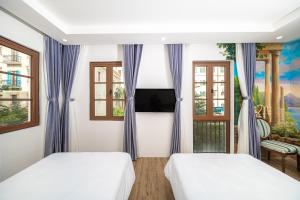 two beds in a room with two windows at Cybele Sunset Hotel Phu Quoc in Phu Quoc