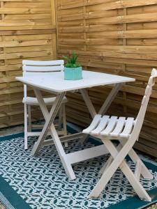 una mesa de picnic blanca con 2 sillas y una maceta en Gîte le charme citadin 55 m² avec extérieur, en Valenciennes
