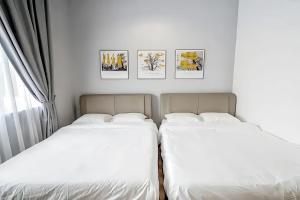 two beds in a bedroom with pictures on the wall at The Quintet Tanah Rata in Tanah Rata