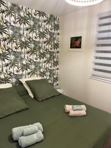 una camera da letto con un letto verde e asciugamani di l’Anita a Théoule-sur-Mer