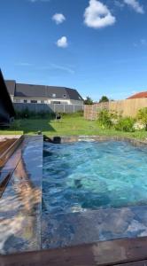 een zwembad met blauw water in een tuin bij Eden Blue Lodge-15 min Compiègne in Chevrières