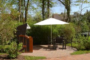 eine Terrasse mit einem Tisch und einem Sonnenschirm in der Unterkunft Haus Friedrichsen 05 in Wyk auf Föhr