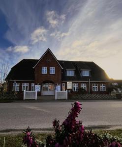 a large brown house with a white fence at Hotel Anka in Norddorf