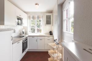 - une cuisine blanche avec des armoires et des fenêtres blanches dans l'établissement Haus Eiderstedt 1, à Wyk auf Föhr
