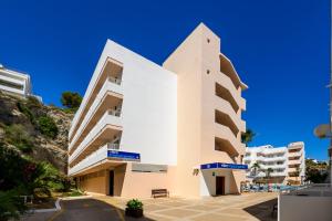 a white building with blue signs on it at Apartamentos Vibra Tropical Garden in Ibiza Town
