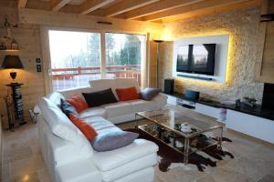 ein Wohnzimmer mit einem weißen Sofa und einem TV in der Unterkunft Le p'tit Suisse, chalet savoyard in Thollon