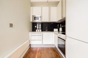 a kitchen with white cabinets and a wooden floor at The Chelsea Collection in London