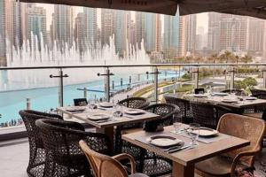 a restaurant with tables and chairs on a balcony with a fountain at Silkhaus luxurious 1BDR in new tower with pool & gym in Dubai