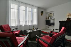 康卡勒L'Ostra 0, appartement haut standing front de mer à Cancale sur le Port de La Houle的客厅配有红色椅子和电视