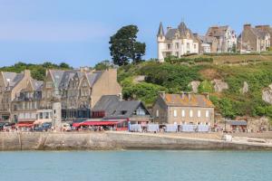 康卡勒L'Ostra 0, appartement haut standing front de mer à Cancale sur le Port de La Houle的水边山丘上的一群建筑物