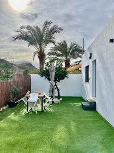 a backyard with green grass and a table and chairs at Villa Don Paco in Las Negras
