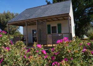 una pequeña casa con un porche con flores rosas en Camping Municipal Le Tindio, en Arzon