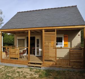 a cabin with a deck with a table and chairs at Camping Municipal Le Tindio in Arzon