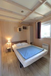a bedroom with a large bed with a blue blanket at Camping Municipal Le Tindio in Arzon