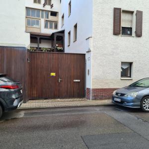 due auto parcheggiate di fronte a una recinzione di legno di Monteurzimmer WG Zimmer Kurzzeitmieter *in a Düren - Eifel