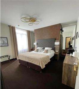 a bedroom with a large bed and a large window at Logis Hôtel & Restaurant - Le Mouton Blanc in Cambrai