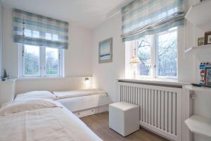 1 dormitorio con 2 camas y 2 ventanas en Haus Leuchtfeuer 4, en Wyk auf Föhr
