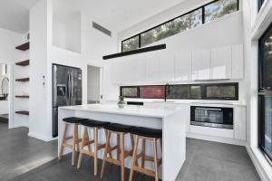 una cucina con bancone bianco e alcune finestre di The Lake House & Apartment a Merimbula