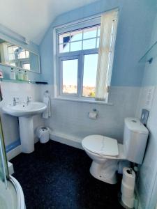 a bathroom with a toilet and a sink and a window at Cleave Court Guest House in Llandudno