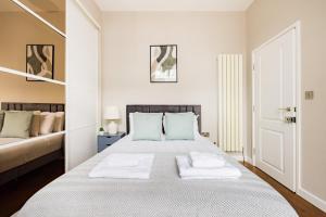 1 dormitorio blanco con 1 cama grande con almohadas azules en The Chelsea Collection en Londres