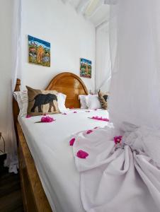 a large white bed with pink flowers on it at Bahati Villa in Kiwengwa