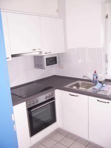 a white kitchen with a sink and a microwave at Ferienhaus Hylla Fischerstraße in Carolinensiel