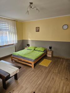 Biała的住宿－Gościniec w Starym Młynie，一间卧室配有一张带绿色床单的床和时钟
