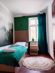 een slaapkamer met groene muren, een bed en een raam bij Dworek Szumilas in Prudnik