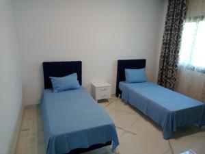 two beds in a room with blue sheets at Villa Jayzy in Hammamet