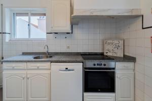 a kitchen with white cabinets and a sink and a stove at Pátios das Marias - Rosas in Setúbal
