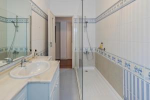 a white bathroom with a sink and a shower at Pátios das Marias - Rosas in Setúbal