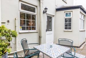 eine Terrasse mit einem Tisch und Stühlen vor einem Haus in der Unterkunft 1 Phoenix Cottages, 403 High Street, Cheltenham in Cheltenham