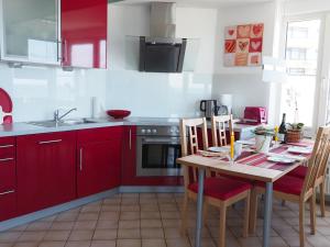 eine Küche mit roten Schränken und einem Tisch mit Stühlen in der Unterkunft AH1 004 - Seeblick in Scharbeutz