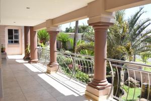 a porch of a house with columns and palm trees at 134 On Ocean View in Amanzimtoti
