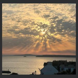a sunset over the water with the sun in the sky at Uno St Ives - Luxury Serviced Accommodation in St Ives