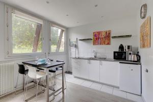 a kitchen with white cabinets and a table with chairs at 235 Home Madrid Concept in Paris