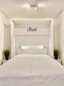 een wit bed in een slaapkamer met 2 planten bij RES 112 - Residenz - Ferienwohnung "Momente" in Scharbeutz