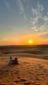 a couple sitting on the beach watching the sunset at R61 Sunset Chalet in Muntarib