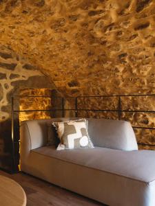 un sofá en una habitación con una pared de piedra en La Grotte, en Corbara