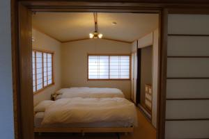 a room with three beds in it with windows at ワタリグラスハウス in Gamō