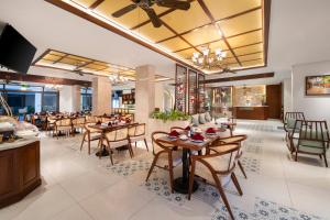 a dining room with tables and chairs and a restaurant at Amina Lantana Hoi An Hotel & Spa in Hoi An