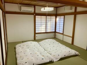 Cette chambre comprend un grand lit et 2 fenêtres. dans l'établissement 南箱根 熱海 貸切別荘 リゾートハウス バンボー, à Kannami