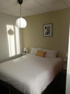 a bedroom with a large white bed with two lights at Hôtel Le Millésime in Meymac