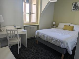 een slaapkamer met een bed, een bureau en een stoel bij Hôtel Le Millésime in Meymac