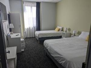 a hotel room with two beds and a window at Hôtel Le Millésime in Meymac +16 photos