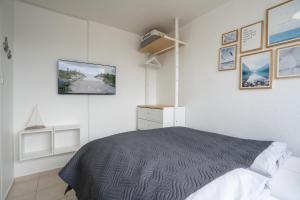 1 dormitorio con 1 cama y TV en la pared en H3 53 - Hanseat - Außenschwimmbad, en Scharbeutz